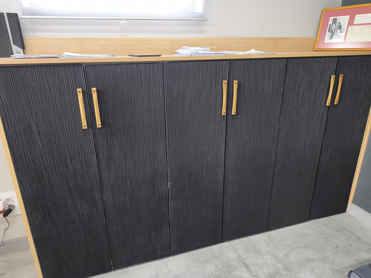 Mueble de madera con puertas texturizadas fabricadas mediante mecanizado CNC, acabado en negro y tiradores de madera natural.